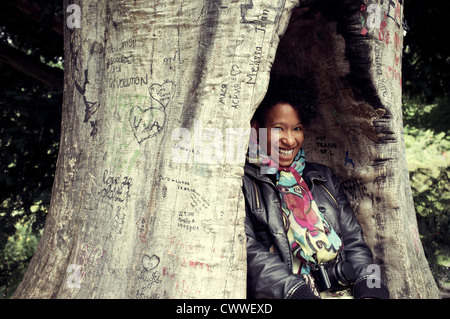 Lächelnde Frau in geschnitzten Baum versteckt Stockfoto