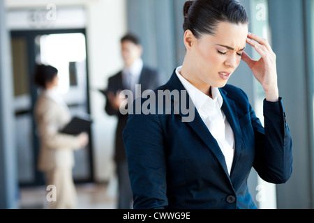 junge Geschäftsfrau mit Kopfschmerzen bei der Arbeit Stockfoto