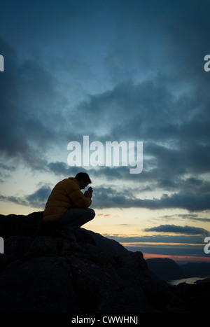 Ein Mann auf dem Gipfel eines Berges zu Gott zu beten. Stockfoto