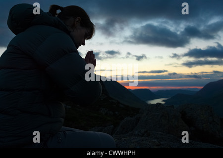 Eine Frau auf dem Gipfel eines Berges zu Gott zu beten. Stockfoto