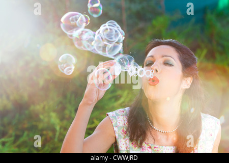 romantische junge Frau aufblasen bunte Seifenblasen im Frühlingspark Stockfoto