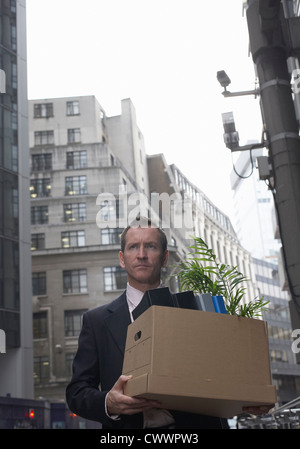 Geschäftsmann mit Box von Büromaterial Stockfoto