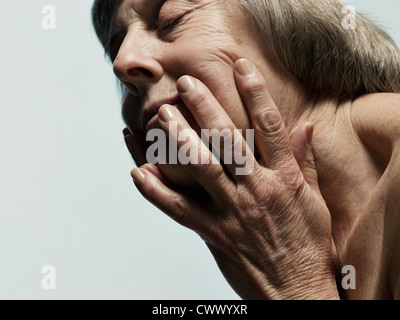 Ältere Frau umklammert ihr Gesicht Stockfoto