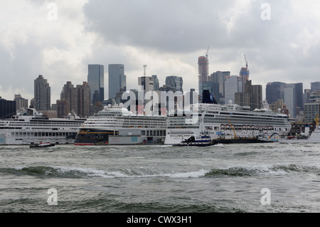 Eine Prozession von Schleppern, vorbei an der Manhattan Cruise Terminal mit drei Kreuzfahrtschiffe im Hafen. Stockfoto