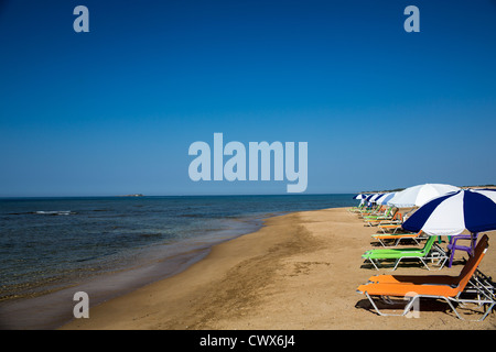 Eine Reihe von leeren farbige Liegestühle am Strand von Agios Georgios, Korfu, Ionische Inseln, Griechenland. Stockfoto