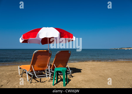 Strand liegen mit Sonnenschirm am Strand von Agios Georgios, Korfu, Ionische Inseln, Griechenland. Stockfoto