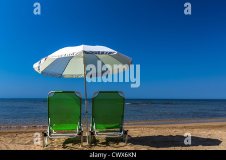 Strand liegen mit Sonnenschirm am Strand von Agios Georgios, Korfu, Ionische Inseln, Griechenland. Stockfoto