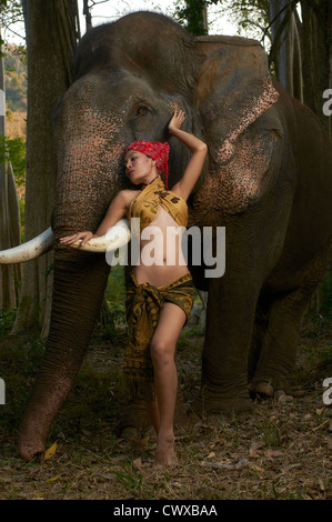 Schöne Thailand Modell stehend mit massiven freundlich asiatischen Elefanten im Dschungel Szene mit Studioblitz in der Natur fotografiert Stockfoto