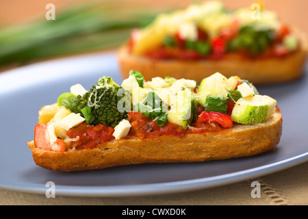 Gebackene vegetarische Open Sandwich (rote Paprika, Brokkoli, Zucchini, Lauch und Käse auf würzige Tomatensauce auf einem Brötchen) Stockfoto