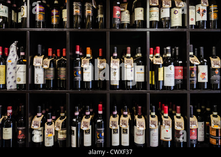 Reihen von roten Wein in Flaschen von lokalen Produzenten schmücken Regale in einem Geschäft in Cortona, Toskana, Italien. Stockfoto