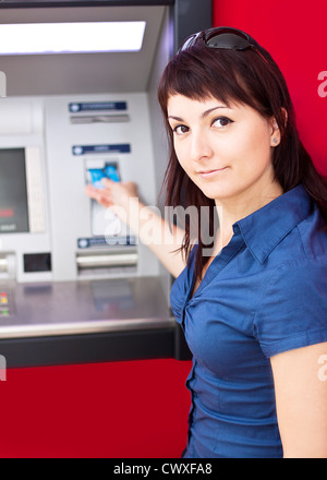 Schöne Frau mit Kreditkarte, sie ist zieht Geld von einem Geldautomaten. Stockfoto