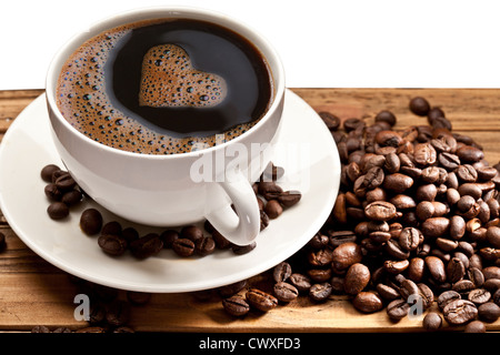 Kaffee-Tasse und Untertasse auf einem Holztisch. Schaumstoff in Form von Herzen. Stockfoto