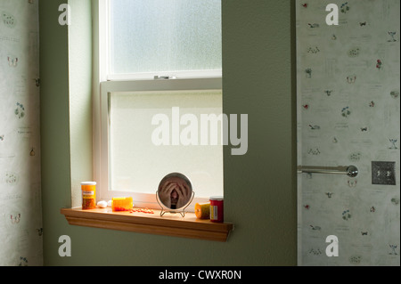 Mannes schreien Gesicht versteckt sich hinter den Händen spiegelt sich im Spiegel mit Tablettenfläschchen auf Fensterbank Stockfoto