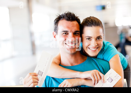 glückliches junges Paar am Flughafen mit Bordkarte Stockfoto