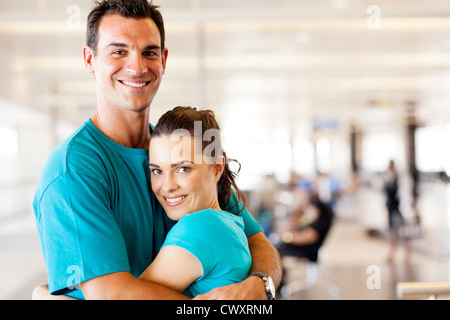 glückliches junges Paar umarmt am Flughafen Stockfoto