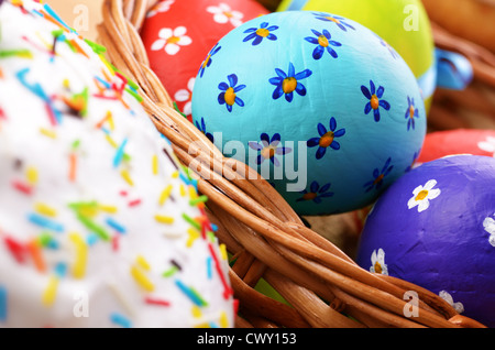 Osterdekoration - Eiern, Kuchen und Korb auf der Tischplatte Stockfoto