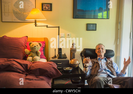 Glücklicher Seniorenarzt, der in einem Sessel sitzt, Teddybärspielzeug auf dem Bett, Schlafzimmer, Altersheim, französisches EHPAD-Pflegeheim, Straßburg Elsass Frankreich Europa Stockfoto