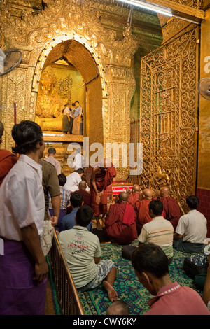 Myanmar, Burma. Mandalay. Mahamuni buddhistischen Tempel. Gläubige sitzen in der Verehrung des Buddha, in Blattgold bedeckt. Stockfoto