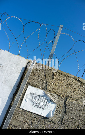 Spulen von Stacheldraht auf einer alten Mauer vor blauem Himmel Stockfoto