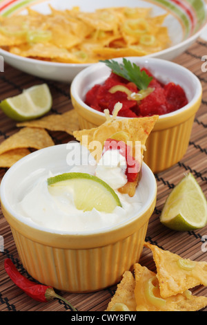 Gerichte von Salsa und Sauerrahm mit einer Schüssel mit echten nachos Stockfoto