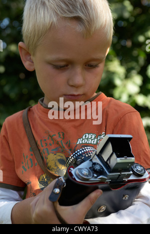 Kind blonde junge halten und Fotografieren mit Vintage-Kamera draußen Sommer Stockfoto