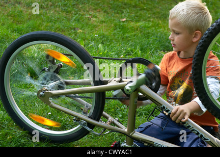 Kind blonde junge Prüfung und Festsetzung seines Fahrrades außerhalb Sommer Stockfoto