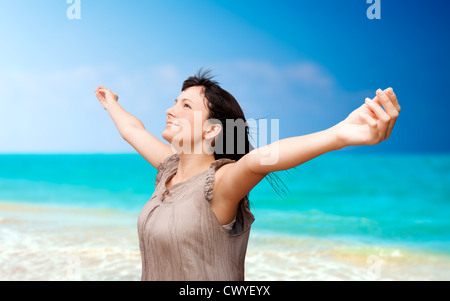 Schöne junge Frau mit erhobenen Armen stand am Strand Stockfoto