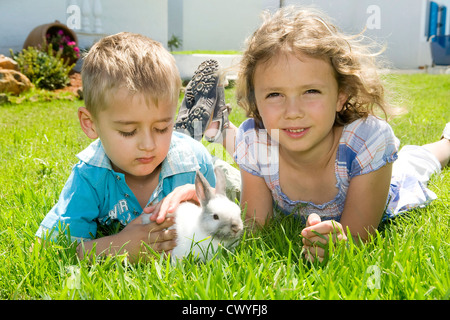 Jungen und Mädchen spielen mit einem Kaninchen Stockfoto