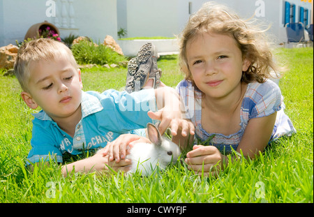 Jungen und Mädchen spielen mit einem Kaninchen Stockfoto