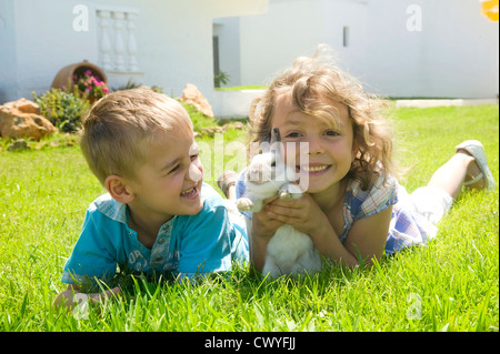 Jungen und Mädchen spielen mit einem Kaninchen Stockfoto