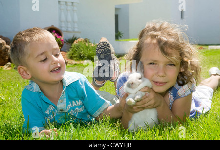 Jungen und Mädchen spielen mit einem Kaninchen Stockfoto