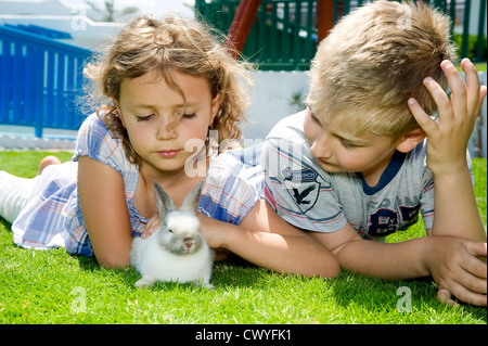 Jungen und Mädchen spielen mit einem Kaninchen Stockfoto