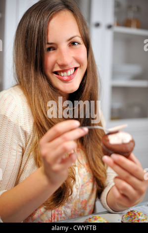 Junge Frau Garnierausstecher Muffin, portrait Stockfoto