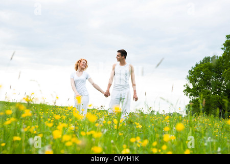 Junges Paar gehen Hand in Hand in Wiese Stockfoto