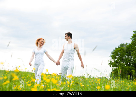 Junges Paar gehen Hand in Hand in Wiese Stockfoto