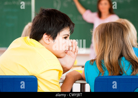 Junge Mädchen im Klassenzimmer Flüstern Stockfoto