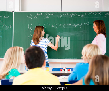 Schulmädchen schreiben Formel an der Tafel Stockfoto