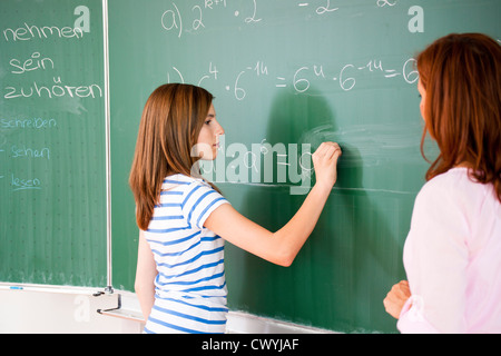 Schulmädchen schreiben Formel an der Tafel Stockfoto