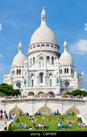 Menschenmengen saßen auf dem Rasen unter Sacre Coeur im Quadrat Louise Michel Paris Frankreich Europa EU Stockfoto