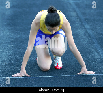 Sportliche Teenager-Mädchen in Startposition auf dem richtigen Weg. Stockfoto