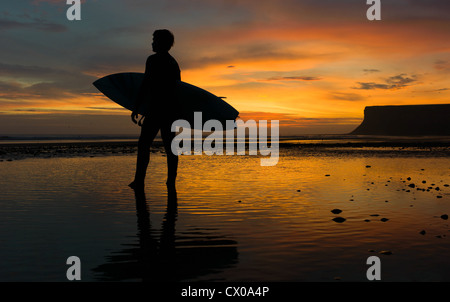 Eine Surfer schaut Saltburn Strand in Cleveland, Großbritannien in Richtung der Brandung Morgen bei Sonnenaufgang. Stockfoto