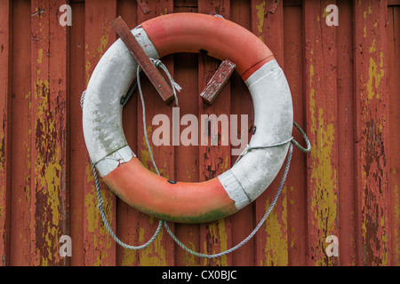 Alten Schwimmweste hängt an der Wand eines Gebäudes mit abblätternde Farbe in rot und gelb Stockfoto