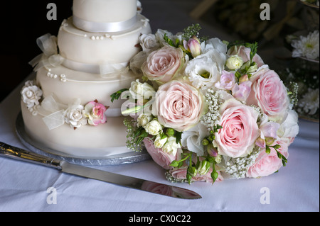 Brautstrauß rosa und weißen Rosen neben der Hochzeitstorte Stockfoto