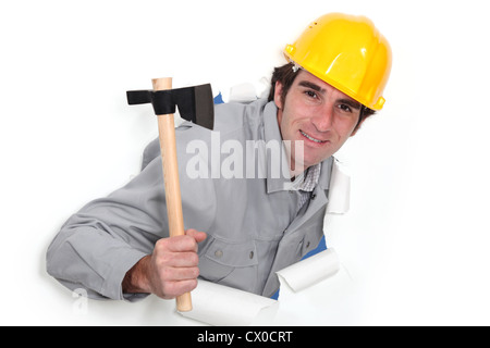 Ein Mann, eine Wand in Papier mit einem Beil herausspringen. Stockfoto