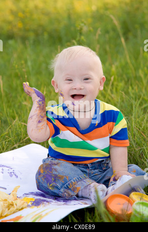 Kleinen Jungen mit Down-Syndrom Malerei Finger malt auf weißem Papier mit einem Lächeln. Glück ist in der Kreativität. Stockfoto