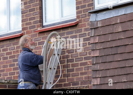 Arbeiter Pumpen Polystyrol Bead Raumwandisolierung in Vorstadthaus in Großbritannien Stockfoto