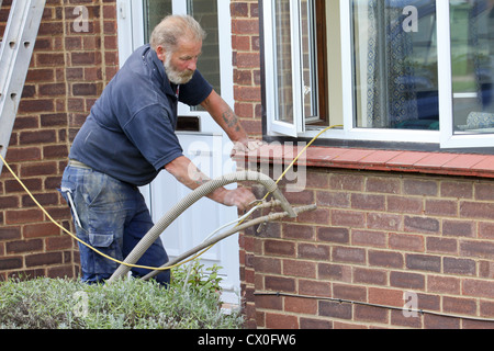 Arbeiter Pumpen Polystyrol Bead Raumwandisolierung in Vorstadthaus in Großbritannien Stockfoto