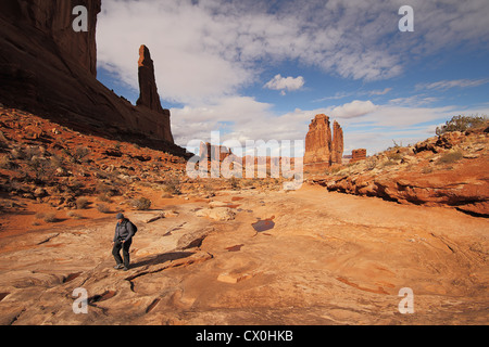 Ein einsamer Wanderer unter den Denkmälern der Sandstein entlang der Park Avenue im Arches National Park in der Nähe von Moab, Utah Stockfoto