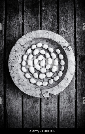 Saubohne Spirale in einer Holzschale auf einem Gartentisch. Monochrom Stockfoto
