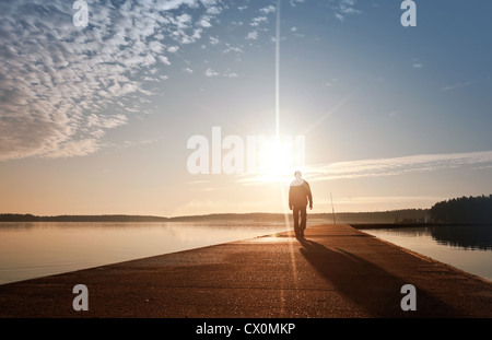 Ein Mann geht auf die Betonpfeiler im Sonnenlicht Stockfoto
